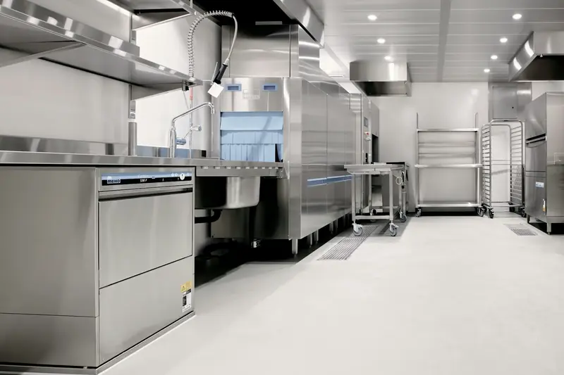 Stainless steel dish station and commercial dishwasher in a restaurant kitchen