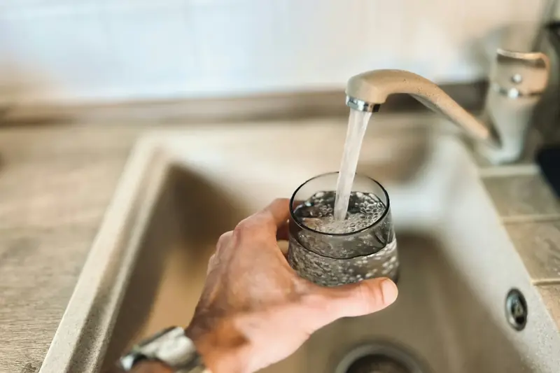 Hand raising a glass of clear water