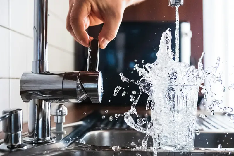 Hand turning on a kitchen faucet over a sink
