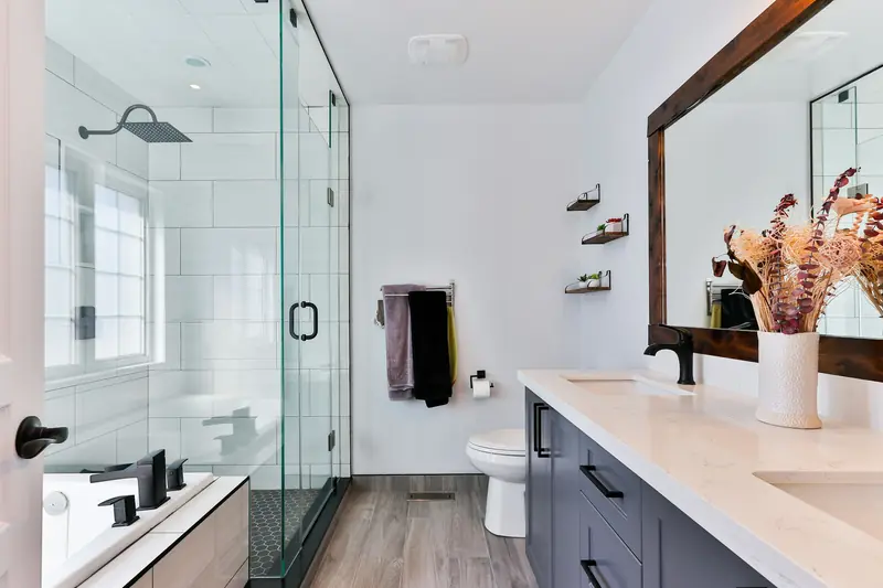 Hotel-style bathroom with a glass shower, vanity and bright fixtures