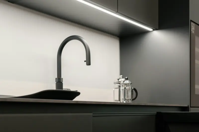 Black gooseneck faucet over a dark sink in a modern kitchen