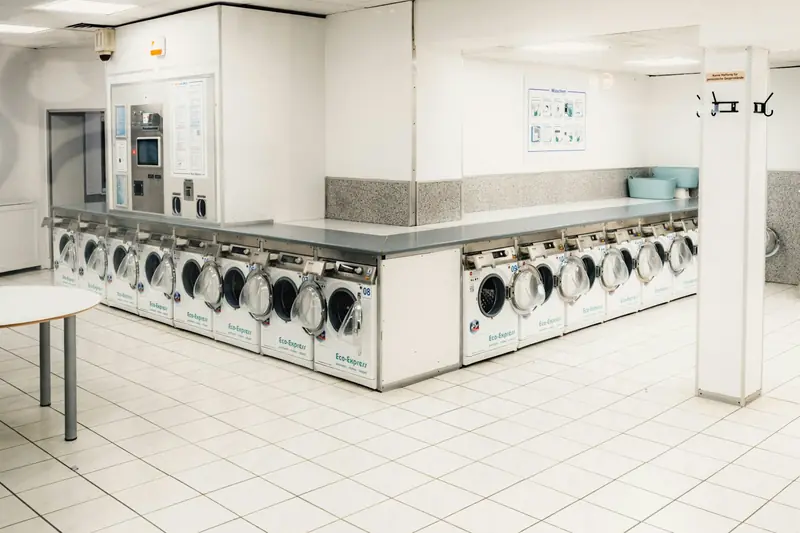 Long row of front-load washing machines in a brightly lit laundromat
