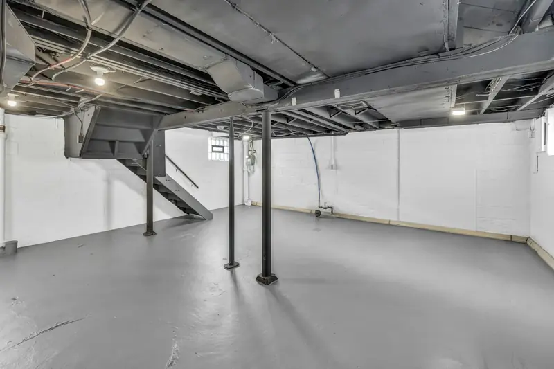 Unfinished basement with exposed joists and support posts, a typical spot for a whole-house softener